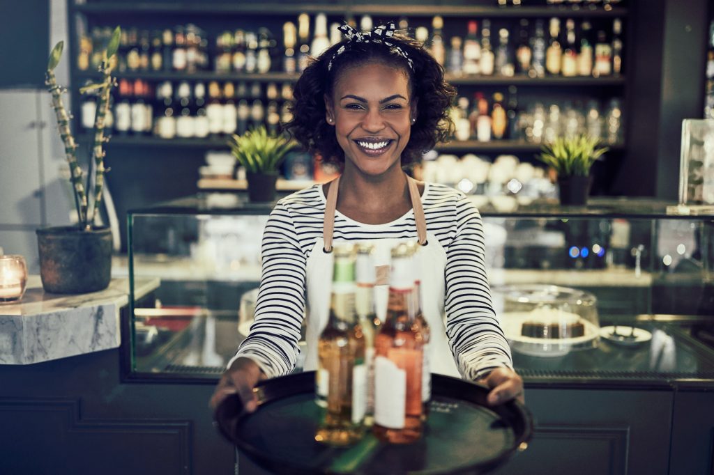 Friendly African restaurant server holding a tray of drinks