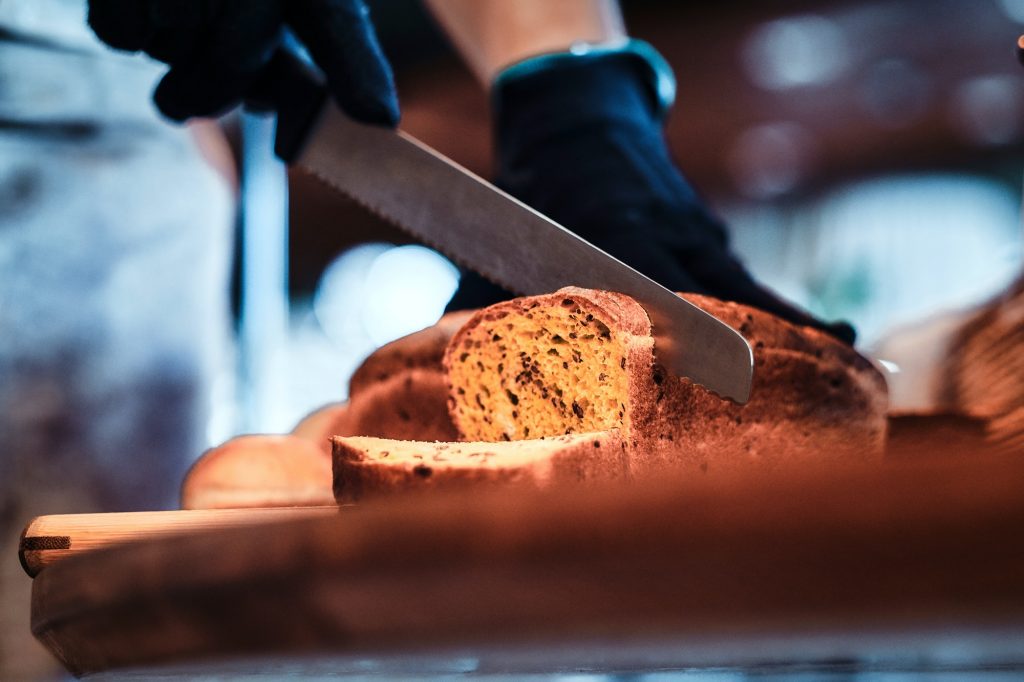 Kitchen worker is slicing bread for lunch