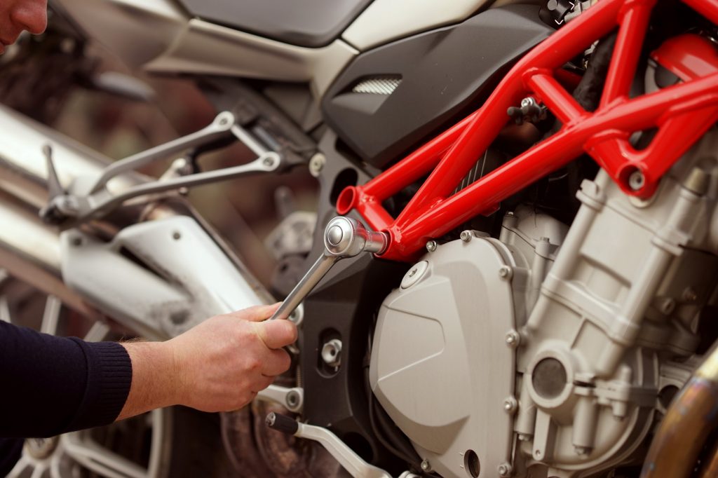 Technician hands of motorbike mechanic repairing a vehicle with a wrench
